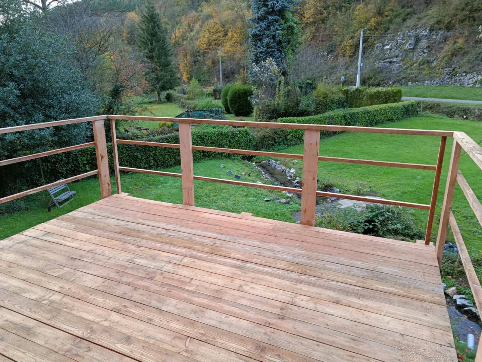 Vue du platelage et de la rambarde en bois de la terrasse Adi’Bois, ouverts sur le jardin